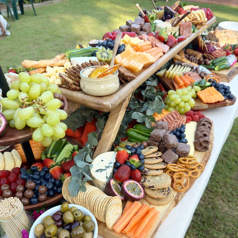 Tiered grazing boards outdoors with grapes and olives