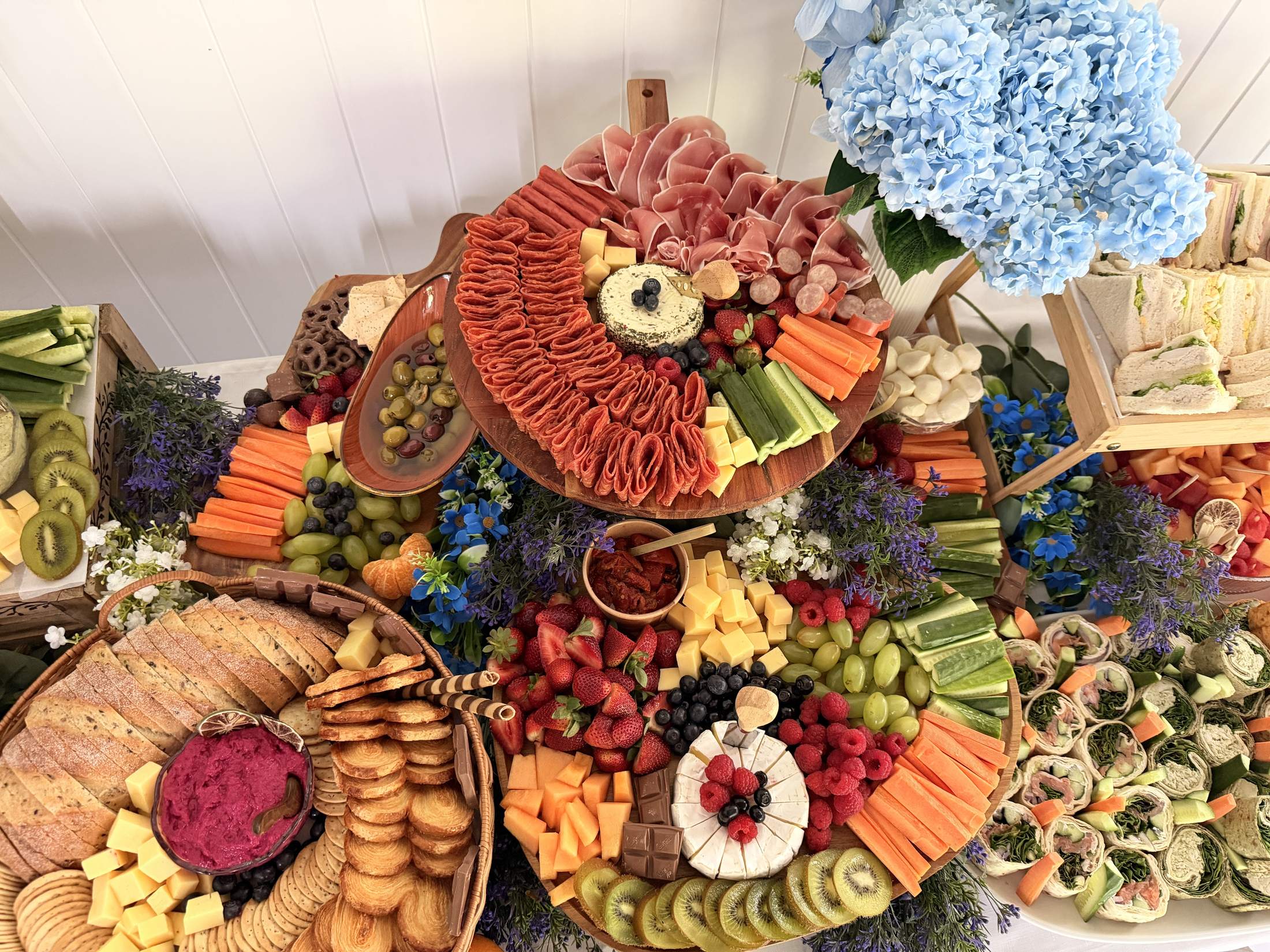 Grazing table from above with blue hydrangeas, lavender, cured meats and fruit