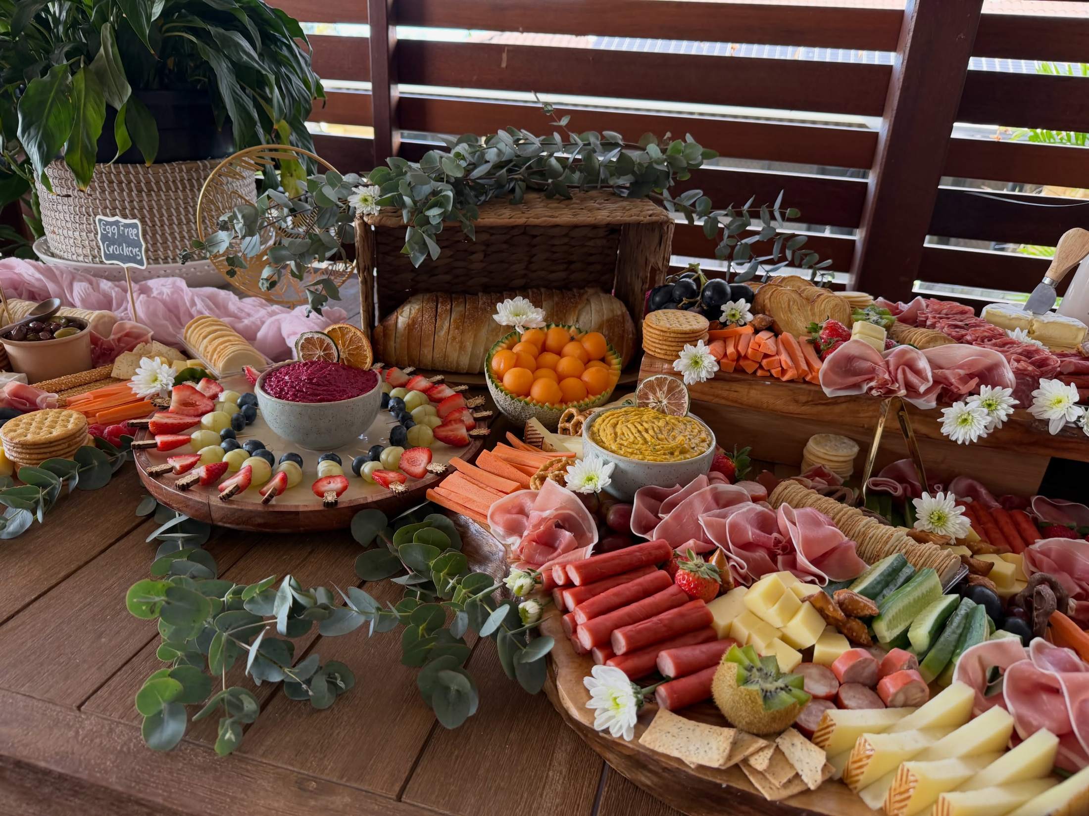 Grazing table on a timber deck with eucalyptus, flowers and dips
